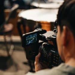 Vidéaste utilisant une caméra professionnelle pour filmer une scène ou un événement religieux.